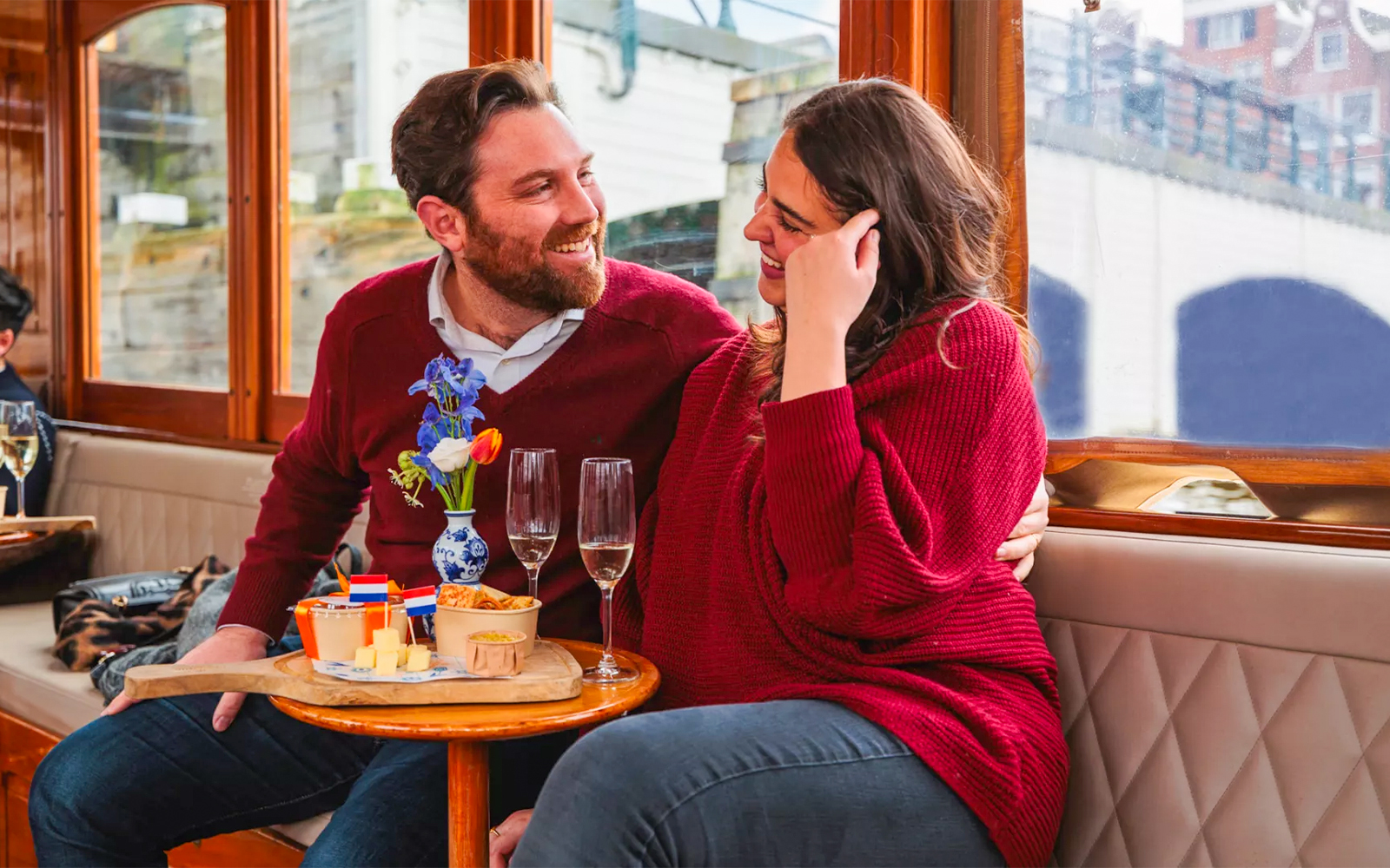 Couple enjoying a romantic cruise in Amsterdam with snacks and drinks.