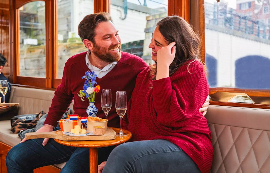 Couple enjoying a romantic cruise in Amsterdam with snacks and drinks.