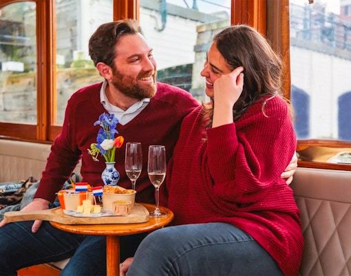 Couple enjoying a romantic cruise in Amsterdam with snacks and drinks.
