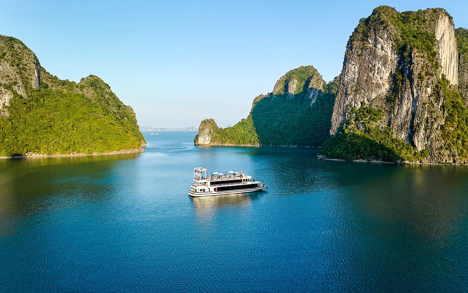 Cruise ship sailing through limestone islands in Ha Long Bay, Vietnam.
