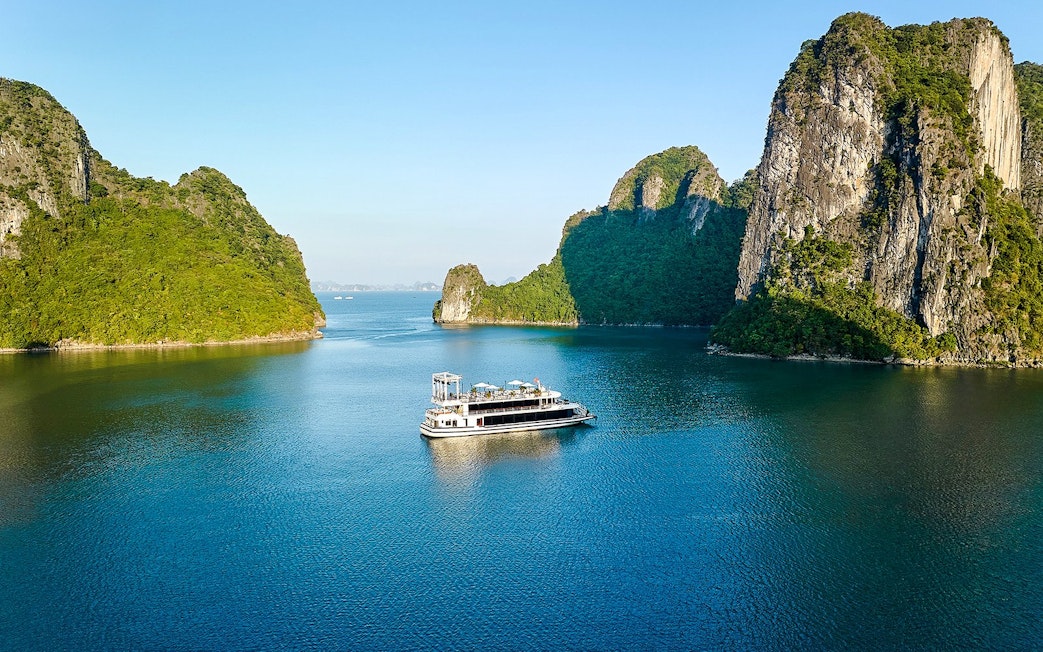 Cruise ship sailing through limestone islands in Ha Long Bay, Vietnam.