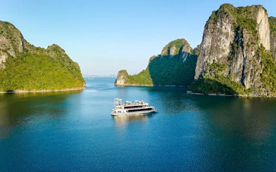 Cruise ship sailing through limestone islands in Ha Long Bay, Vietnam.