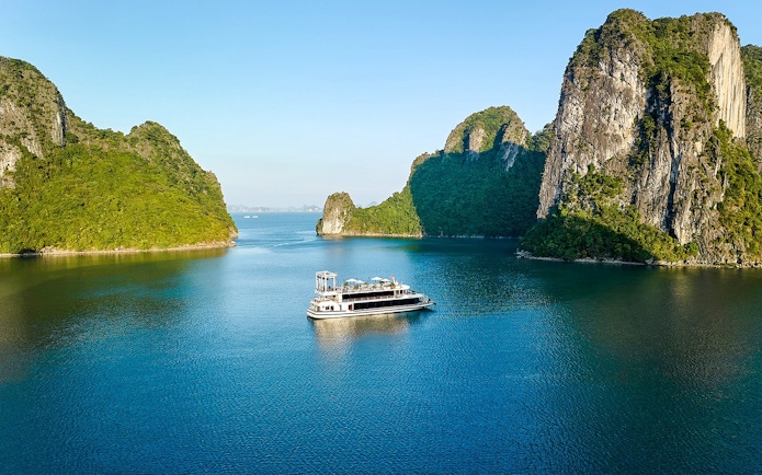 Cruise ship sailing through limestone islands in Ha Long Bay, Vietnam.