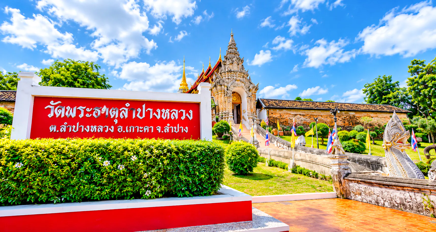 Lampang temple entrance with ornate architecture and flags, Chiang Mai day trip.