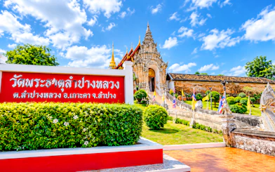 Lampang temple entrance with ornate architecture and flags, Chiang Mai day trip.