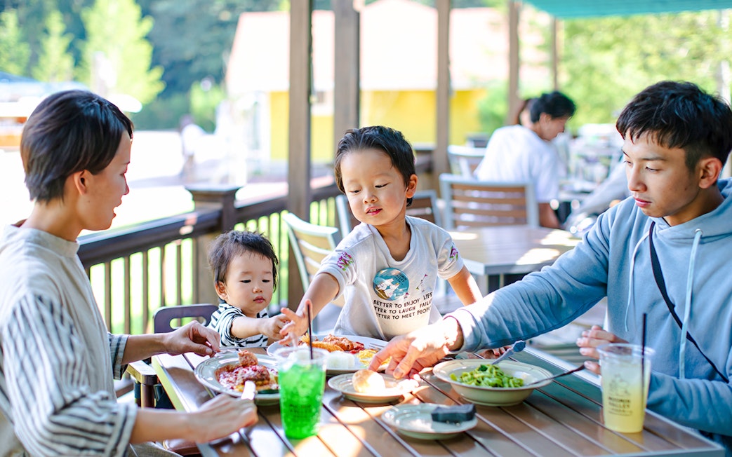 Family dining outdoors at Moominvalley Park, enjoying a meal together.