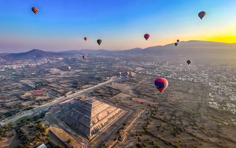 Hot air balloons floating over the Pyramid of the Sun in Teotihuacan, Mexico.
