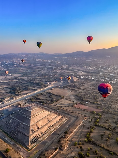 Hot air balloons floating over the Pyramid of the Sun in Teotihuacan, Mexico.