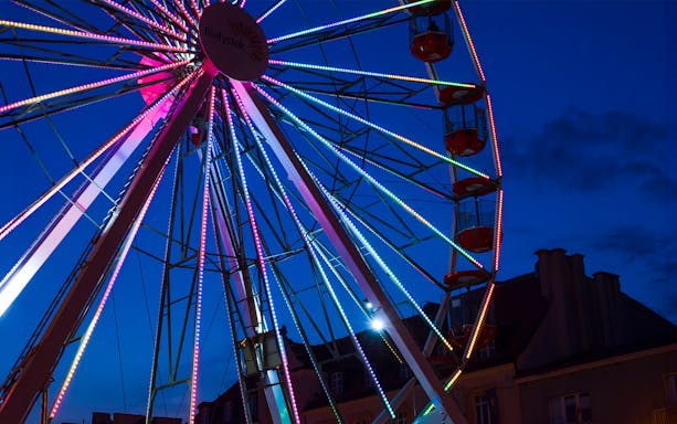 Ferris wheel with colorful lights against a darkening Brussels sky.
