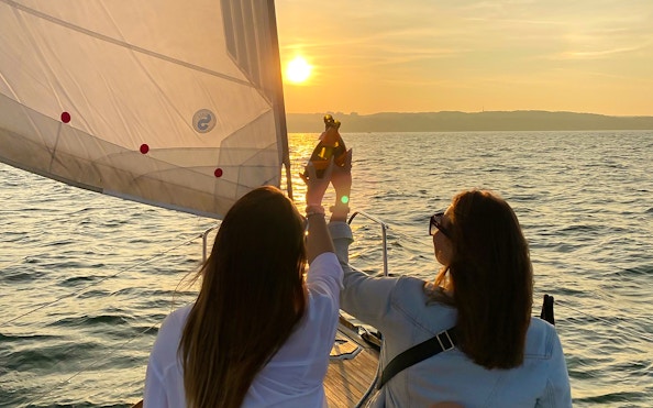 Sailing at sunset from Sopot Pier with people toasting on deck.