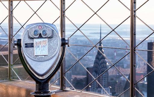 Observation deck binoculars overlooking New York City skyline from Empire State Building.