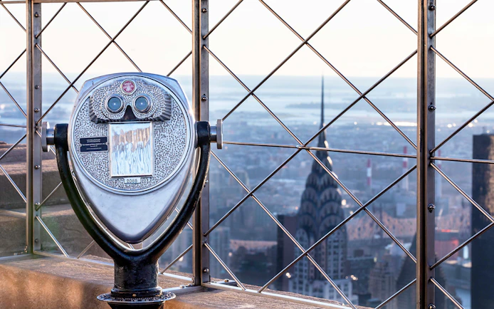 Observation deck binoculars overlooking New York City skyline from Empire State Building.