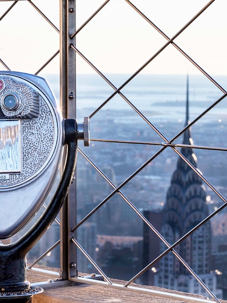 Observation deck binoculars overlooking New York City skyline from Empire State Building.