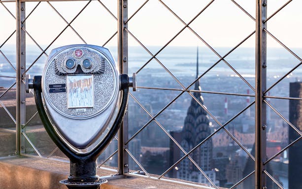 Observation deck binoculars overlooking New York City skyline from Empire State Building.