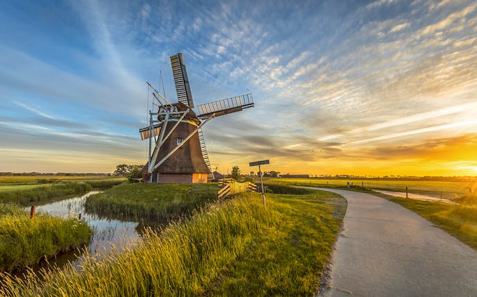 Windmill in the Dutch countryside at sunset, part of a full-day guided tour.