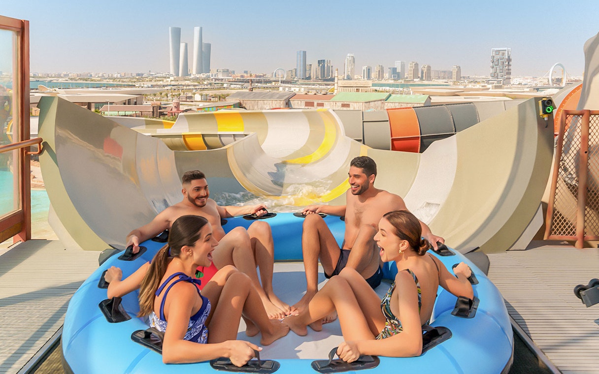 Visitors enjoying a group water ride at Meryal Waterpark with city skyline in background.
