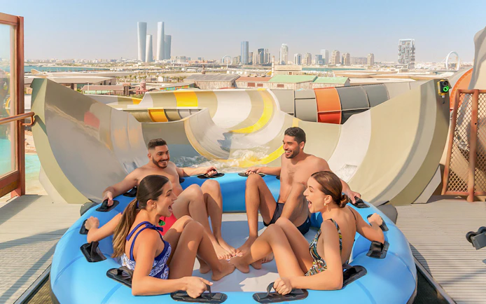 Visitors enjoying a group water ride at Meryal Waterpark with city skyline in background.