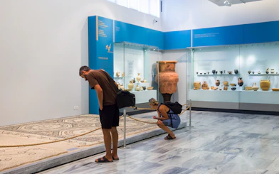 Visitors examining artifacts at Heraklion Archaeological Museum, Crete, Greece.