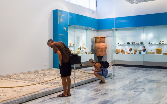 Visitors examining artifacts at Heraklion Archaeological Museum, Crete, Greece.