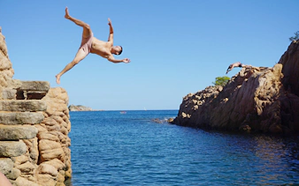 Cliff jumping into the sea on Costa Brava near Tossa de Mar, Spain.