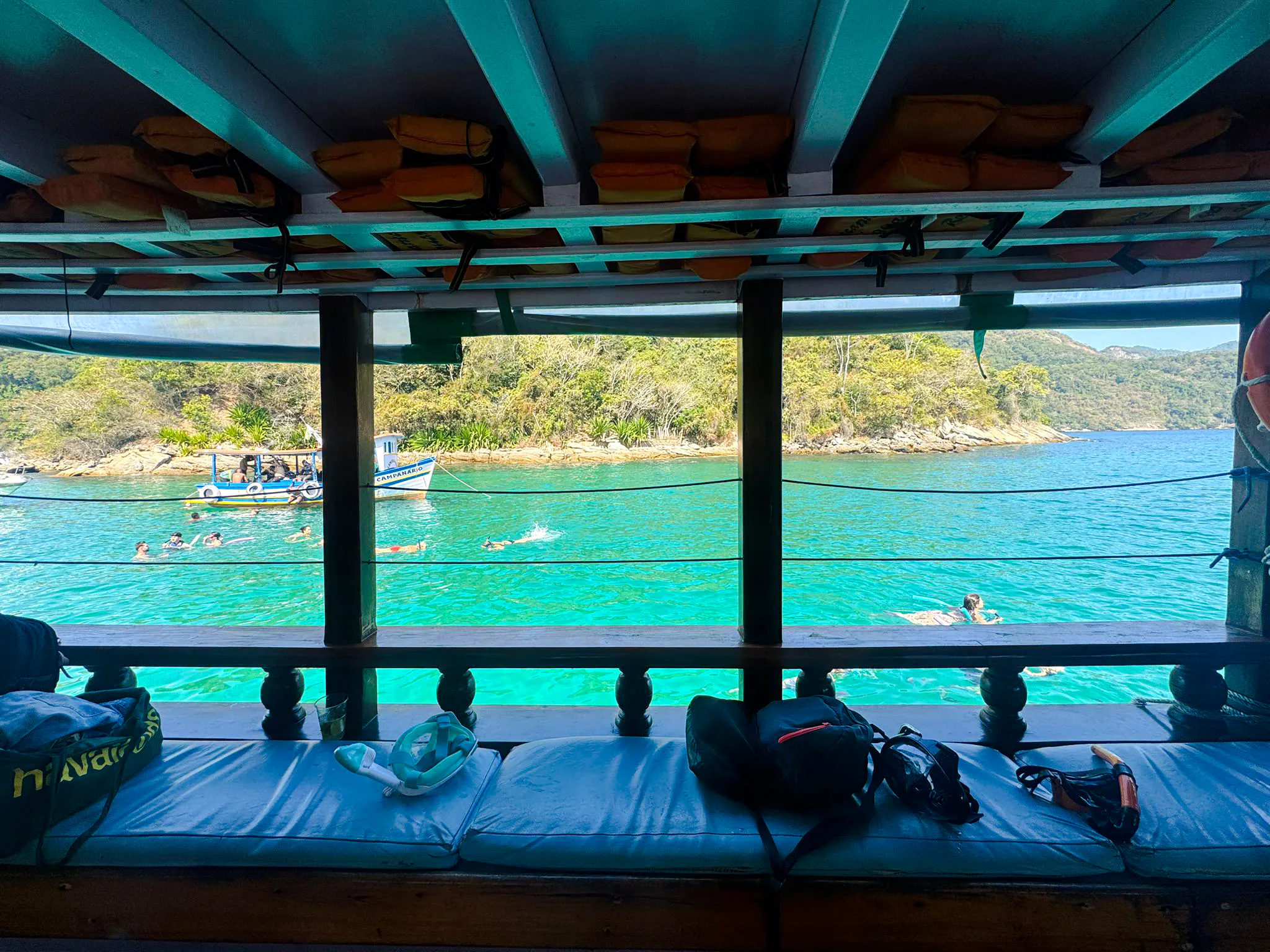 View from a boat of people swimming in clear waters at Arraial do Cabo, Brazil.