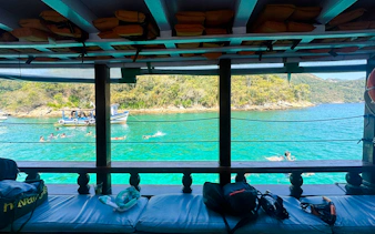 View from a boat of people swimming in clear waters at Arraial do Cabo, Brazil.