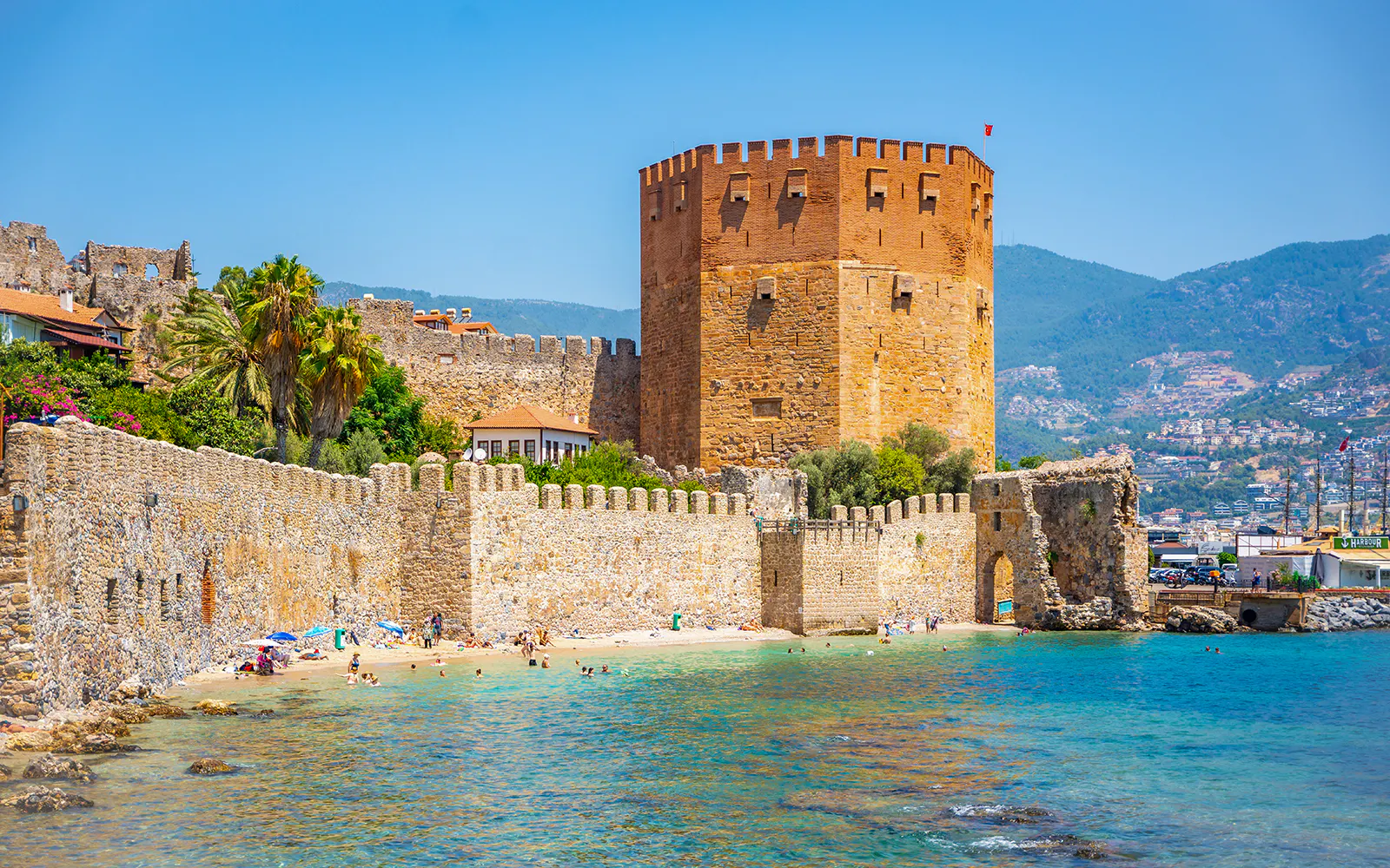 Alanya Red Tower and beach with tourists, Turkey.