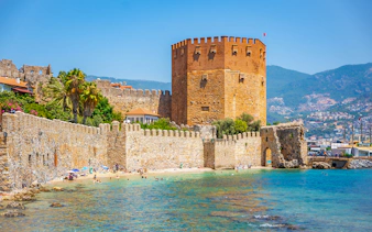 Alanya Red Tower and beach with tourists, Turkey.