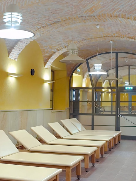 Loungers inside Rudas Thermal Spa with arched brick ceiling and warm lighting.