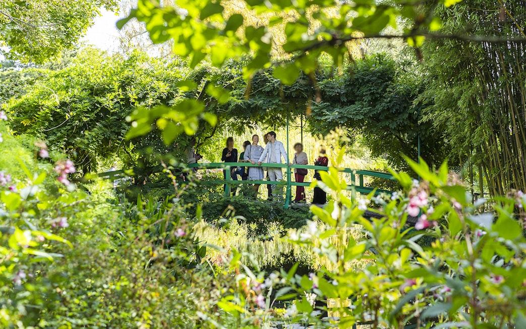 Visitors on Japanese bridge in Monet's Garden with guide.