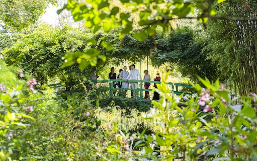 Visitors on Japanese bridge in Monet's Garden with guide.