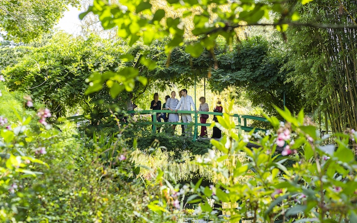 Visitors on Japanese bridge in Monet's Garden with guide.