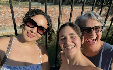 Three people smiling by a canal in Milan's Navigli district during a self-guided city exploration game.