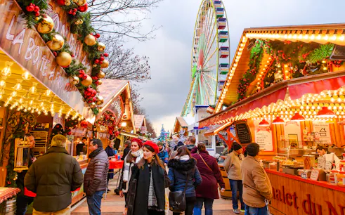 Paris Christmas Market with festive stalls and a Ferris wheel in the background.
