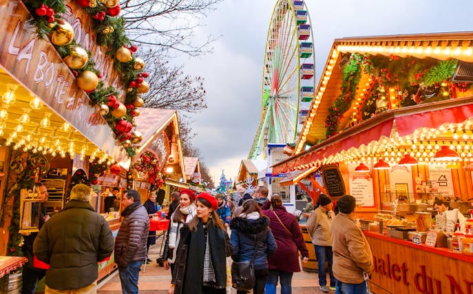 Paris Christmas Market with festive stalls and a Ferris wheel in the background.