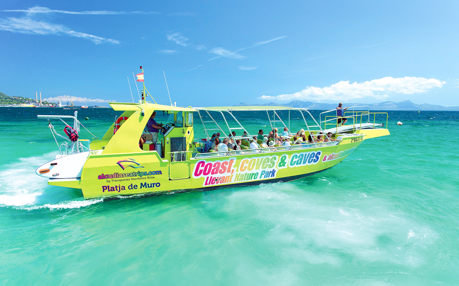 Boat with tourists on Alcudia's turquoise waters, heading to explore caves and snorkel.