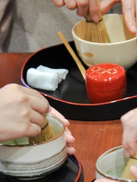 Tourists whisking matcha in bowls during a tea-making class.