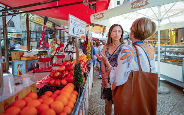 Palermo market scene with fresh fruit and juice stand during guided art and food walking tour.