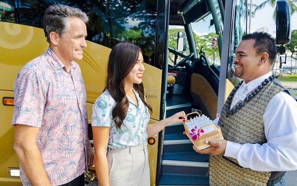 Driver welcoming passengers with a gift basket before boarding Royal Star tour bus.