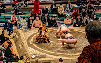Sumo wrestlers competing in a ring during a private grand sumo tournament in Japan.