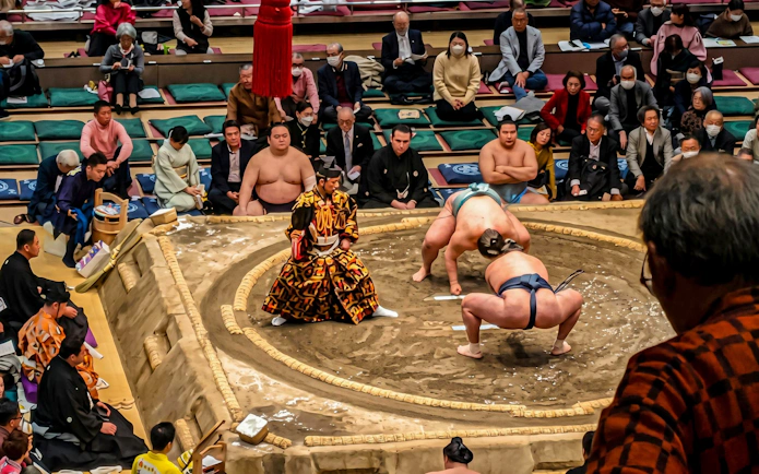Sumo wrestlers competing in a ring during a private grand sumo tournament in Japan.