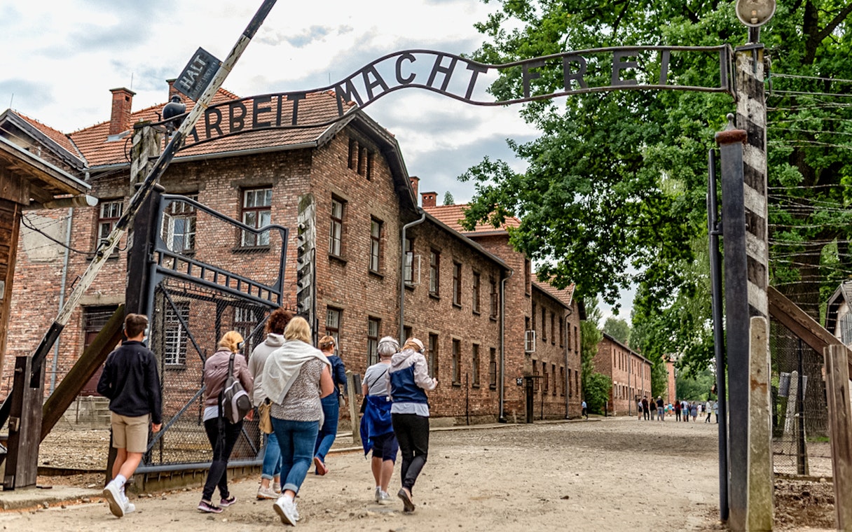 Visitors walking under the "Arbeit Macht Frei" gate at Auschwitz Concentration Camp.