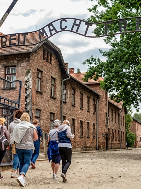 Visitors walking under the "Arbeit Macht Frei" gate at Auschwitz Concentration Camp.