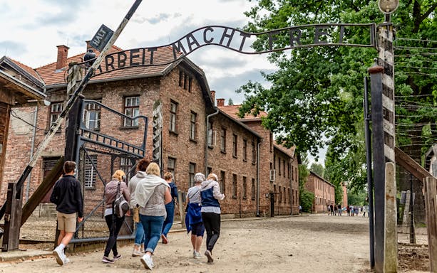Visitors walking under the "Arbeit Macht Frei" gate at Auschwitz Concentration Camp.