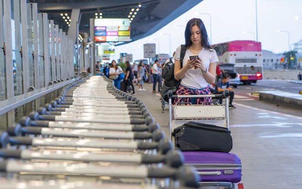 Traveler with luggage cart at Palermo Airport terminal.