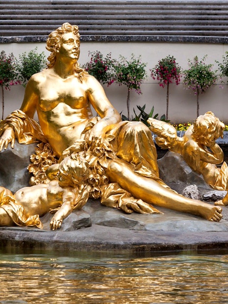 Golden statue in Linderhof Palace garden fountain, part of a day trip from Munich to Neuschwanstein.