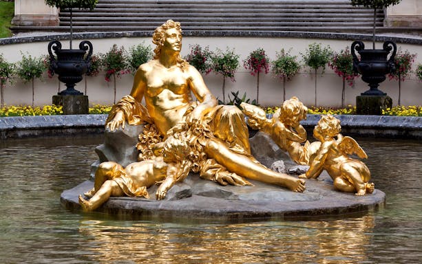 Golden statue in Linderhof Palace garden fountain, part of a day trip from Munich to Neuschwanstein.