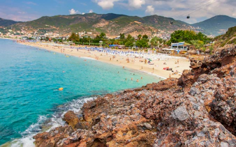 Alanya beach with cable cars and mountains in the background.