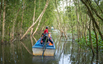 Motorboat navigating through lush trees in Mekong Delta.