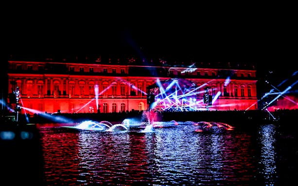 Versailles Palace illuminated with lights during an electro music event.